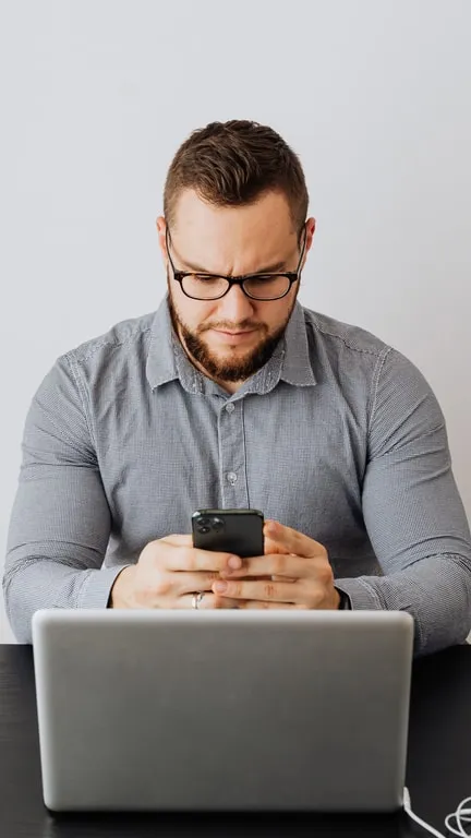 Finished vertical clip of a man comparing his phone and his laptop